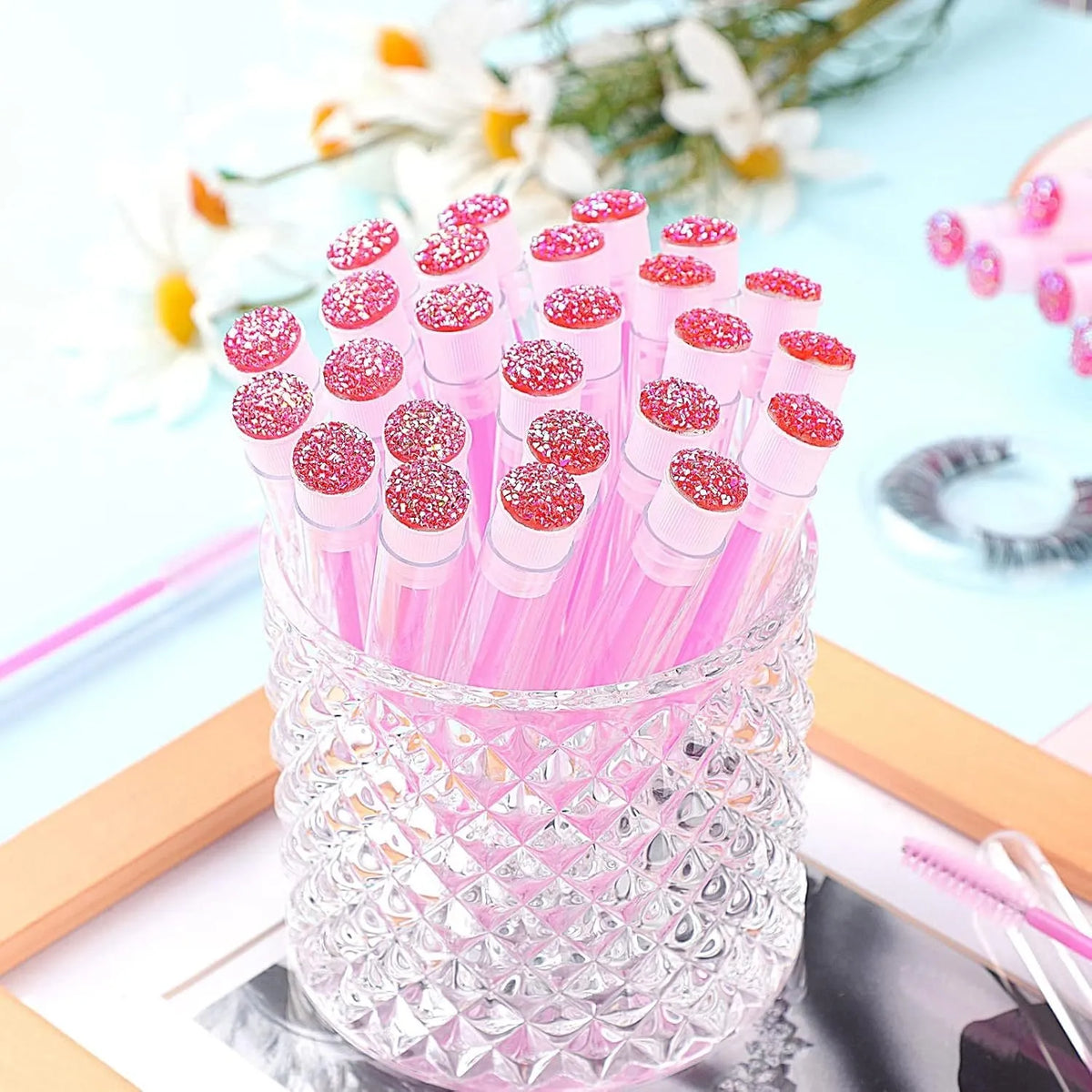 Set of coloured disposable eyelash mascara brushes inside clear plastic protective tubes.