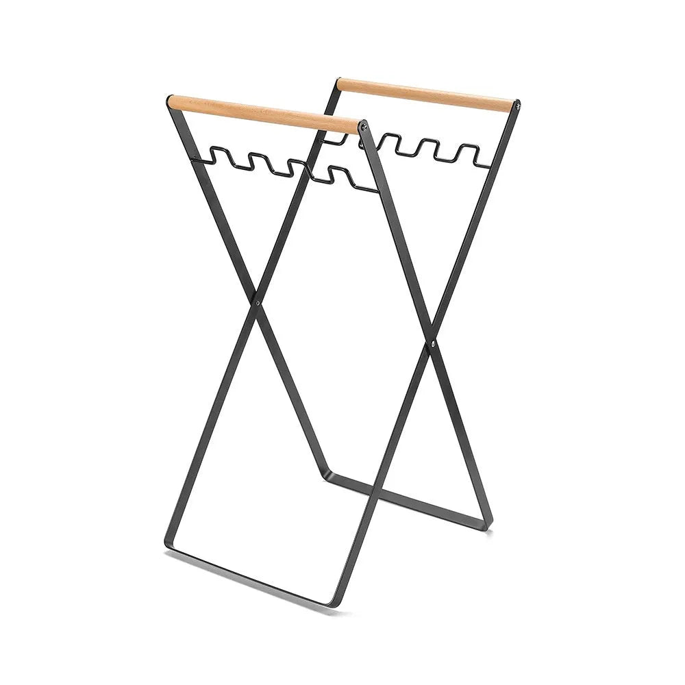 Black foldable iron trash storage hanger with wooden handle holding a bin bag outdoors.