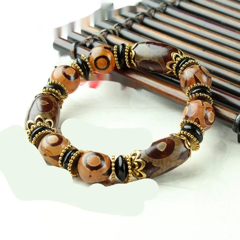 Distressed agate Tibetan bead bracelet with three-eye motifs and polished finish.