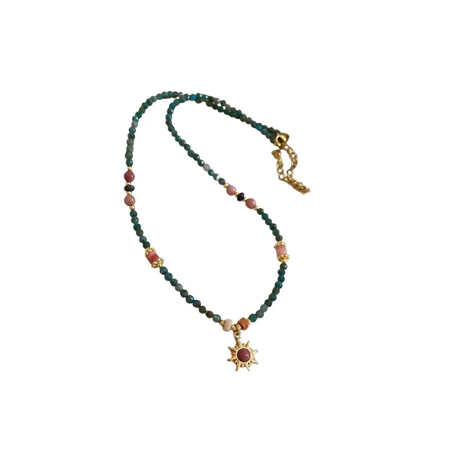 Freshwater pearl sun necklace with blue stone pendant on a gold-tone adjustable chain.