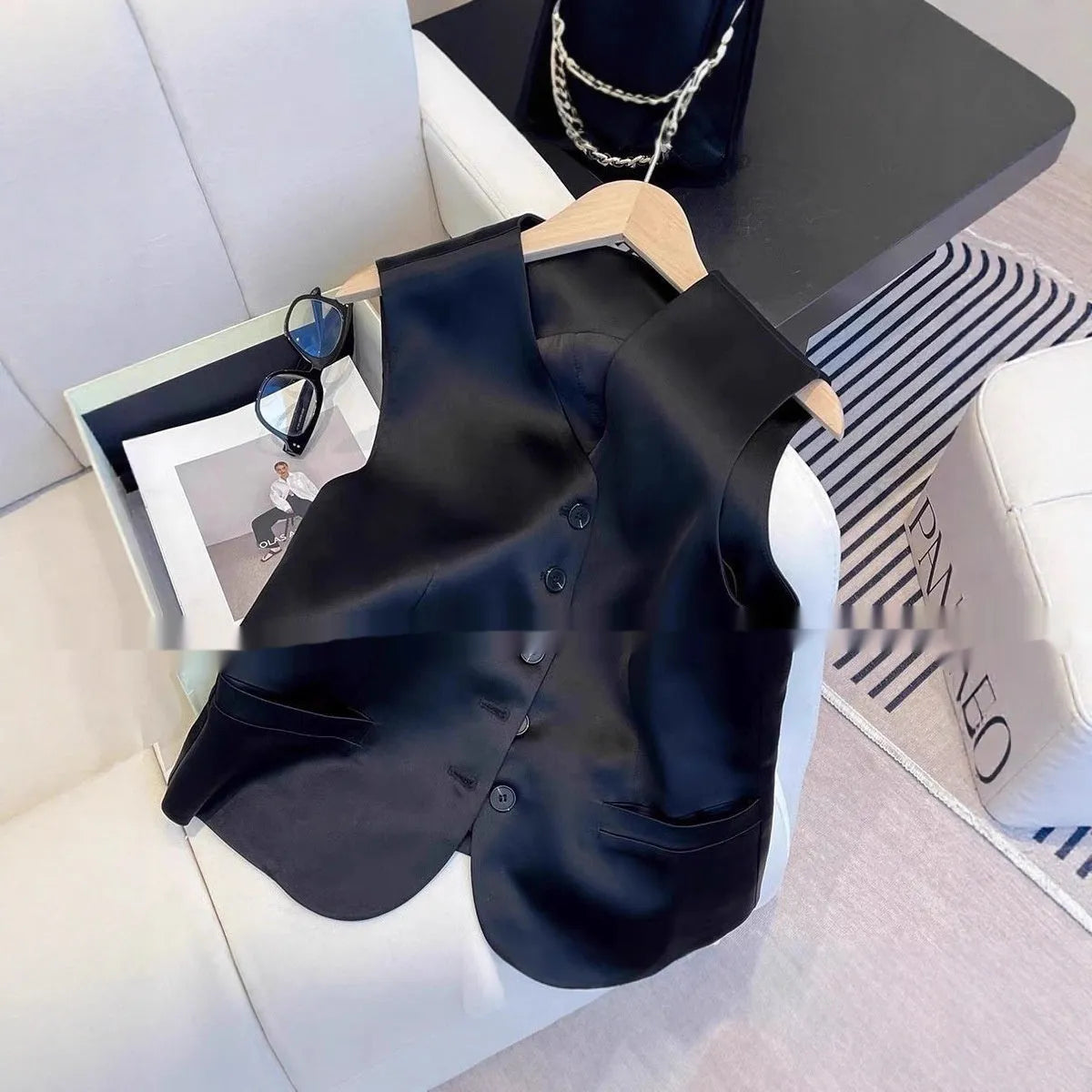 Black satin ladies' sleeveless vest with loose fit and splicing details on solid background