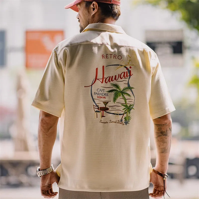 A light apricot men's shirt with a bamboo plant pattern and a relaxed Cuban collar.