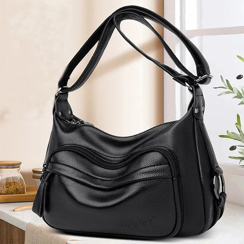 Large blue women's crossbody shoulder bag with a zipper and soft handle, shown with internal organiser pockets.