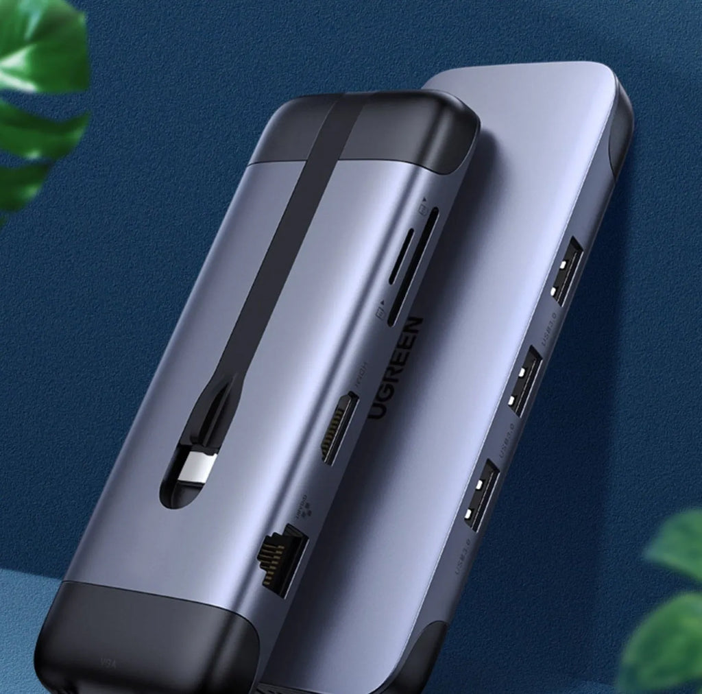 USB-C dock expansion adapter with short cable next to a laptop, showing HDMI, USB, and Ethernet ports.