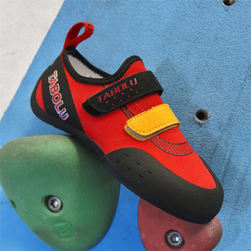 A pair of beginner rock climbing shoes with Velcro straps, shown in a black and red colour scheme.