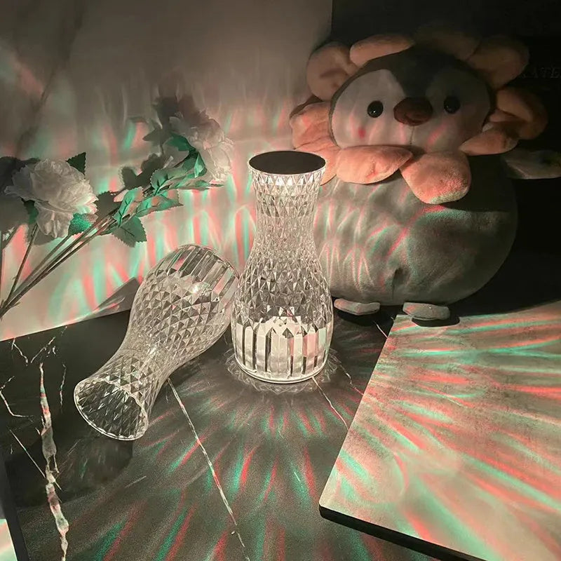 Vase-shaped transparent crystal table lamp with LED colour-changing lights on wooden surface