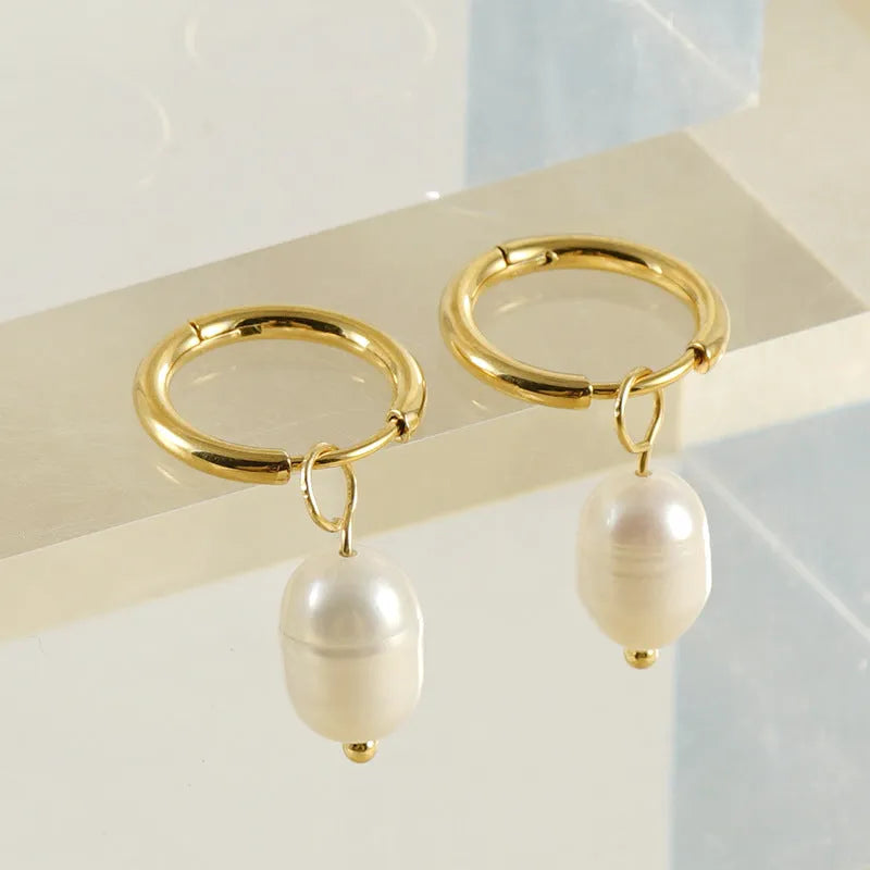 A pair of gold-coloured geometric earrings with a central pearl, made from stainless steel.