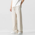 Men's beige loose-fit straight-leg linen trousers with drawstring waist, shown on a model.