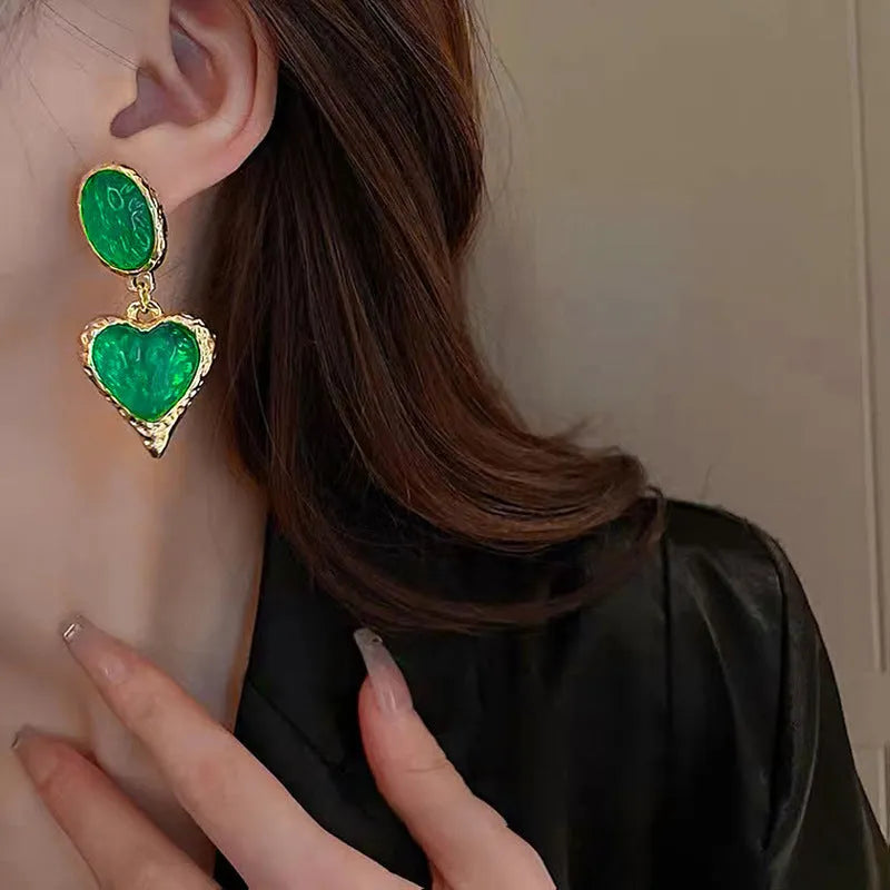 Four pairs of oval love heart stud earrings with silver needle pleated detailing in purple, red, green, and yellow-white colours