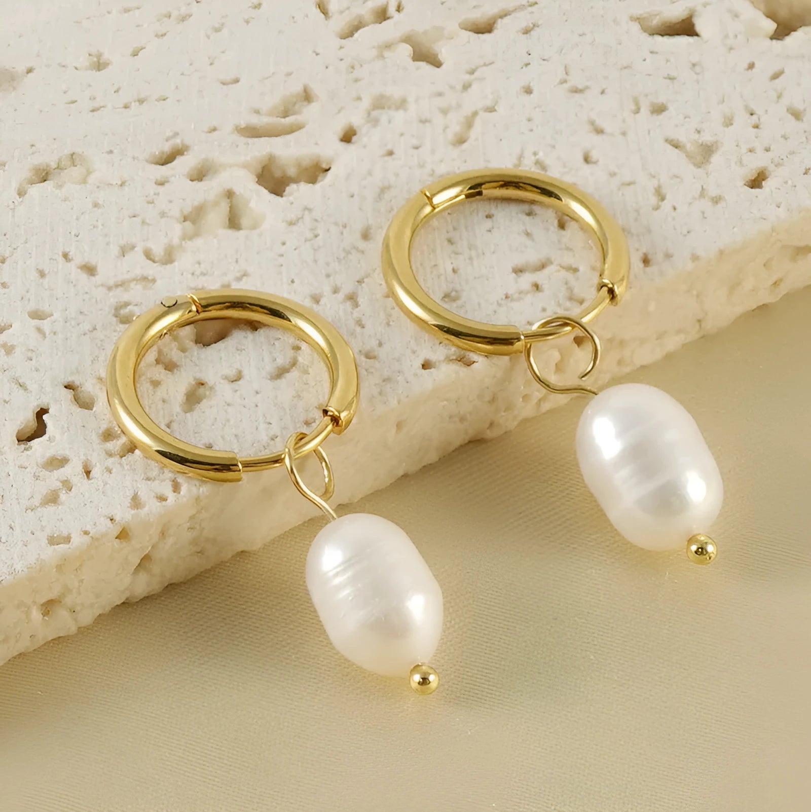 A pair of gold-coloured geometric earrings with a central pearl, made from stainless steel.