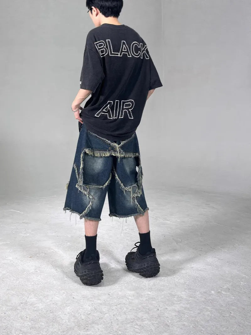 Blue loose-fit men's denim shorts with a frayed hem and a large retro star design on the leg.