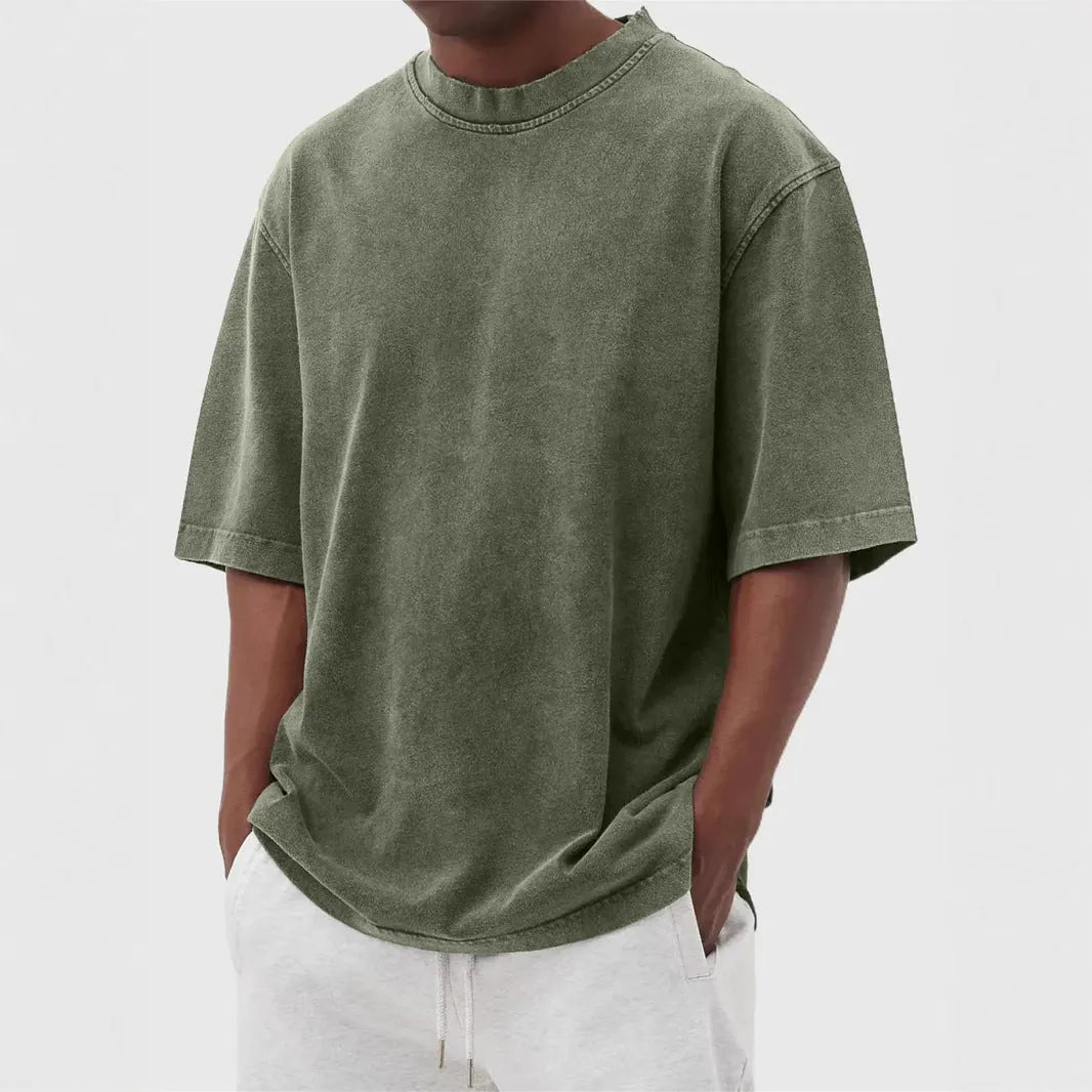 A man's loose-fit, stone-washed pullover t-shirt in a solid colour, shown on a hanger.