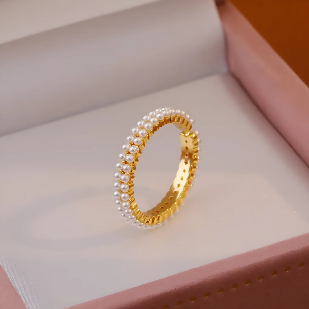 Gold geometric ring with open mouth design and pearl elements on female hand