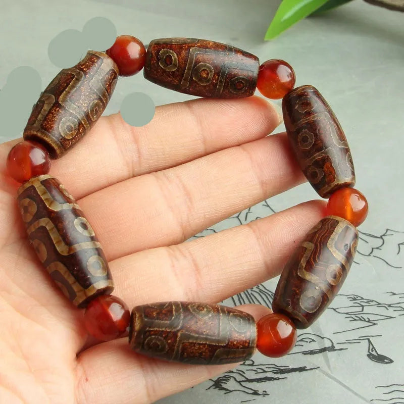 Distressed agate Tibetan bead bracelet with three-eye motifs and polished finish.