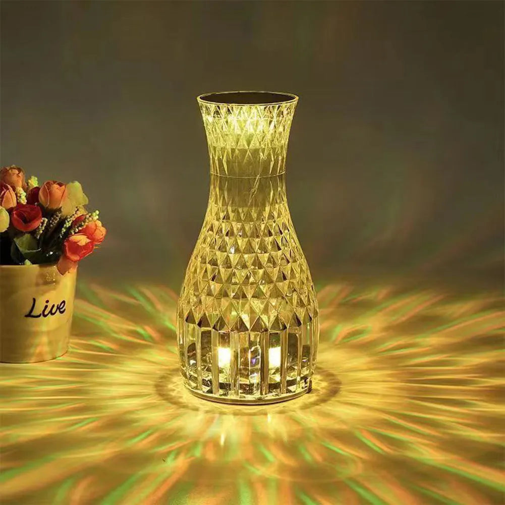 Vase-shaped transparent crystal table lamp with LED colour-changing lights on wooden surface