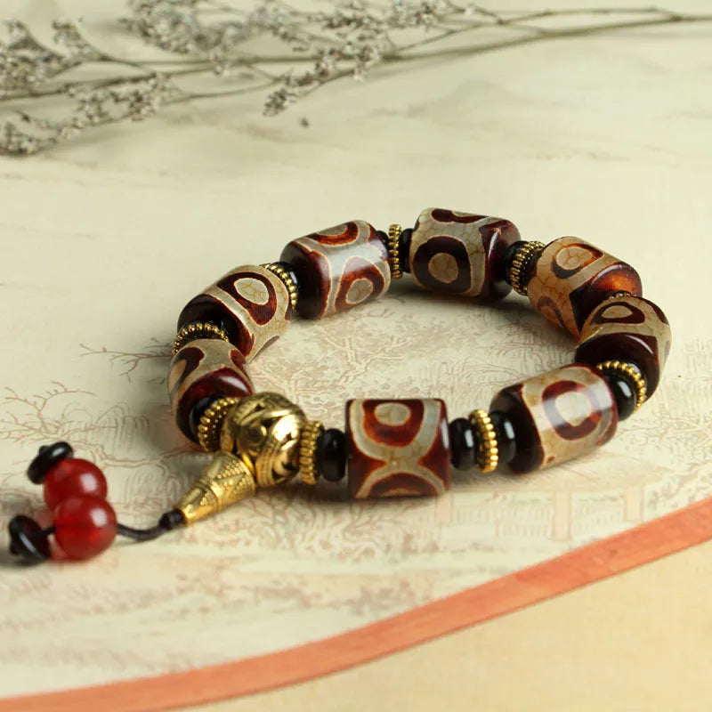 Distressed agate Tibetan bead bracelet with three-eye motifs and polished finish.