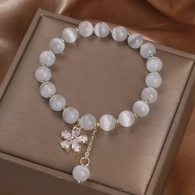 Women's single loop white cat's eye stone bracelet with flower tassel and morganite safety buckle.