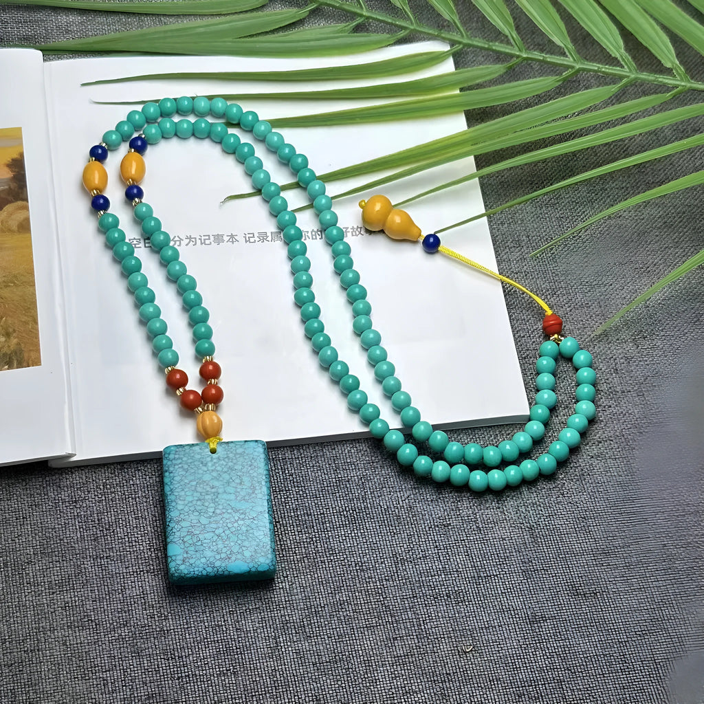 Turquoise mesh flower lucky pendant necklace with ball bead chain on a white background