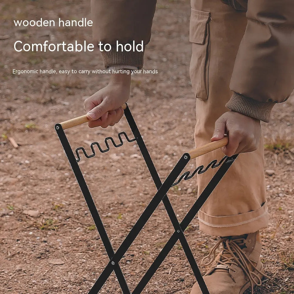 Black foldable iron trash storage hanger with wooden handle holding a bin bag outdoors.