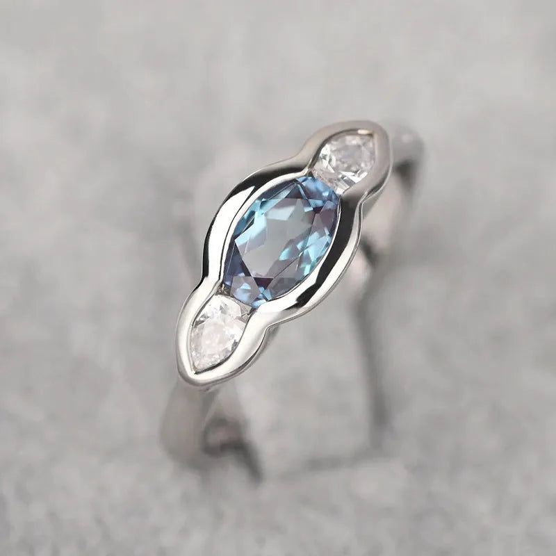 Geometric ellipse copper ring with inlaid zircon stones in white gold finish on a grey background