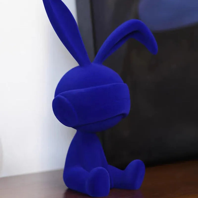 Green suede blindfold rabbit resin table ornament on a wooden desk