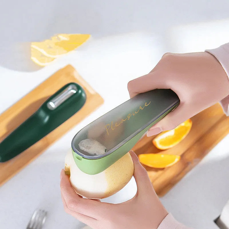 Dark green kitchen peeler with stainless steel blade stored inside its clear plastic storage tube.