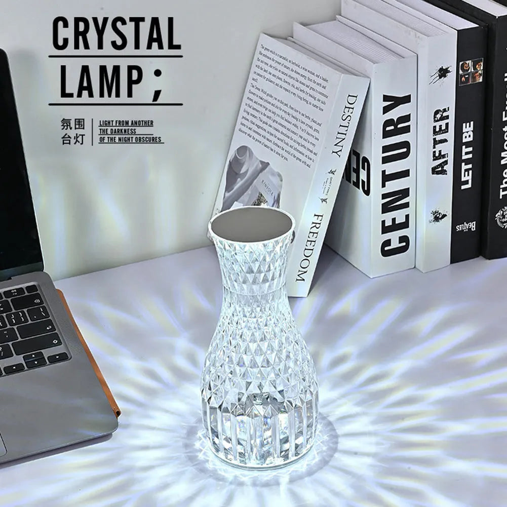 Vase-shaped transparent crystal table lamp with LED colour-changing lights on wooden surface
