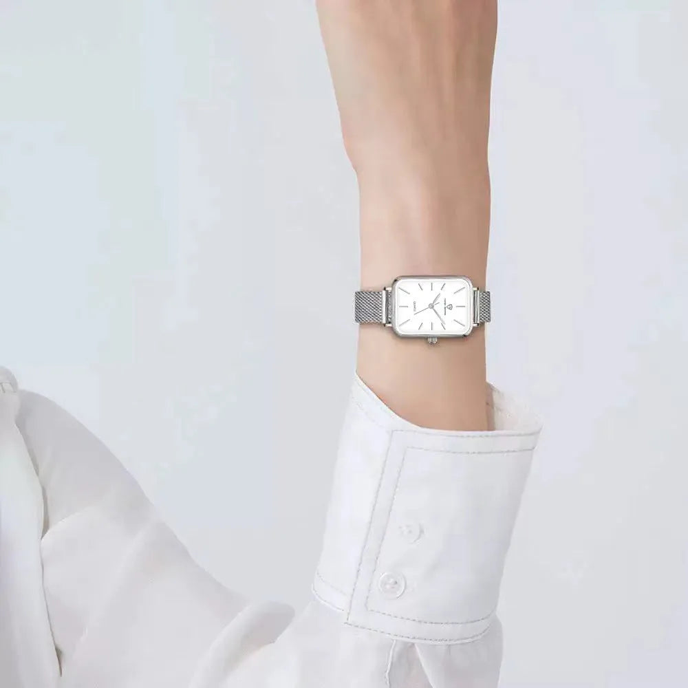 Rose gold women's waterproof quartz watch with woven steel strap on wrist.
