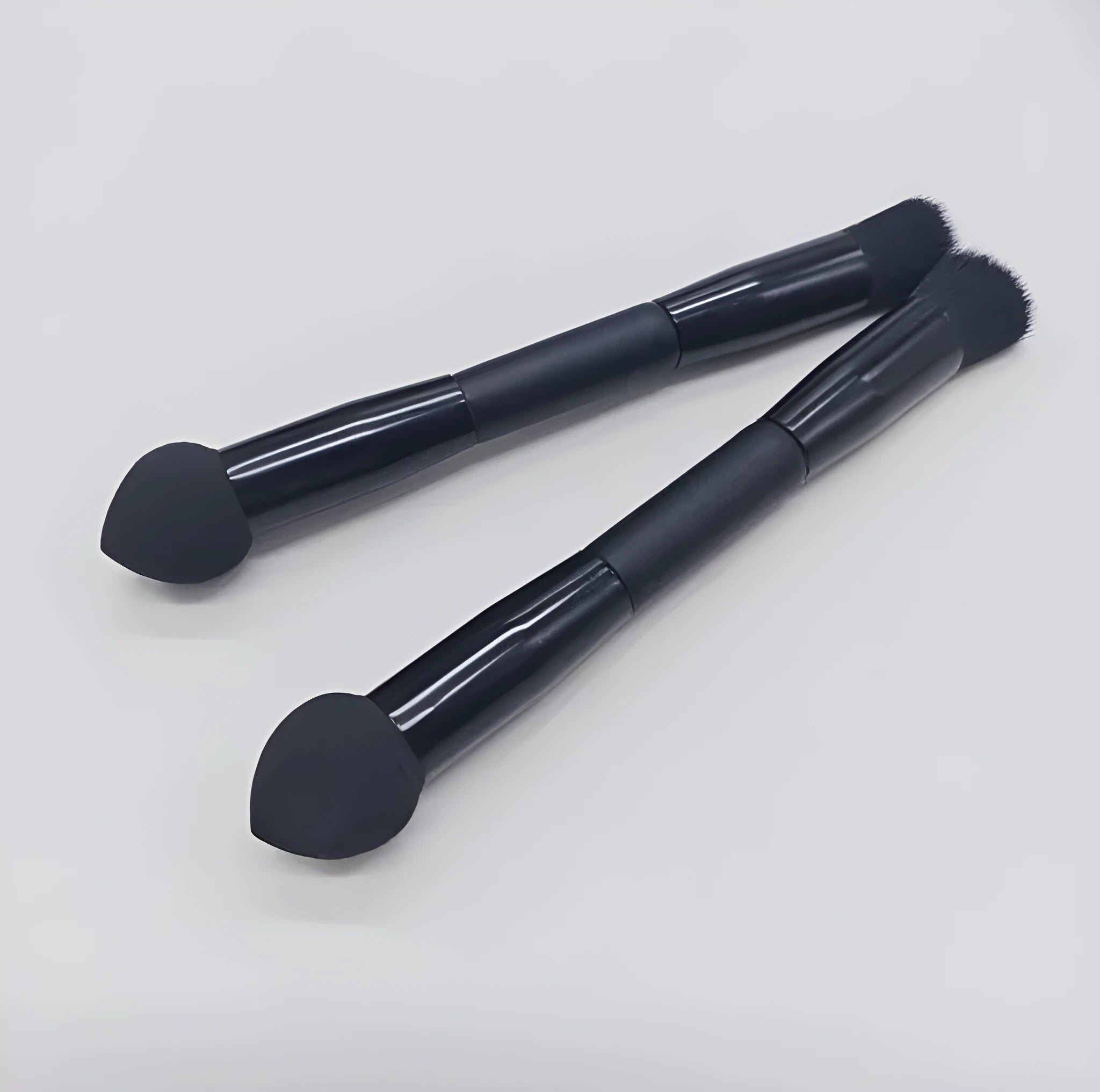 Double-headed makeup brush with black sponge end and pointed brush end on wooden handle