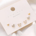 Three pairs of heart-shaped alloy earrings in gold, black, white and pink colours
