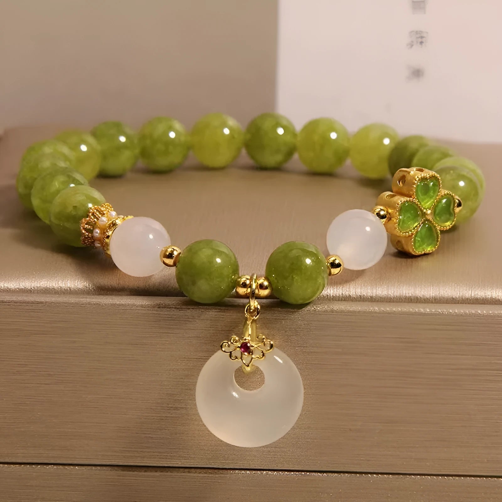 Women's green tourmaline bracelet with four-leaf clover safety buckle on a wrist.