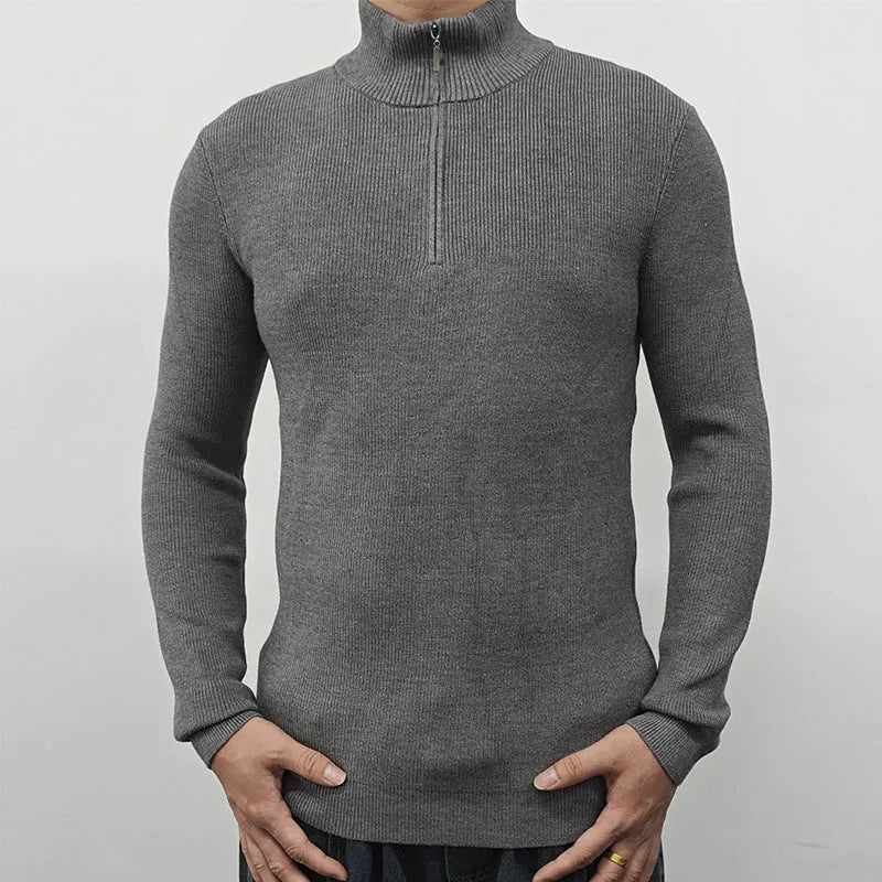 Man wearing a grey zip-up half-turtleneck sweater with long sleeves.