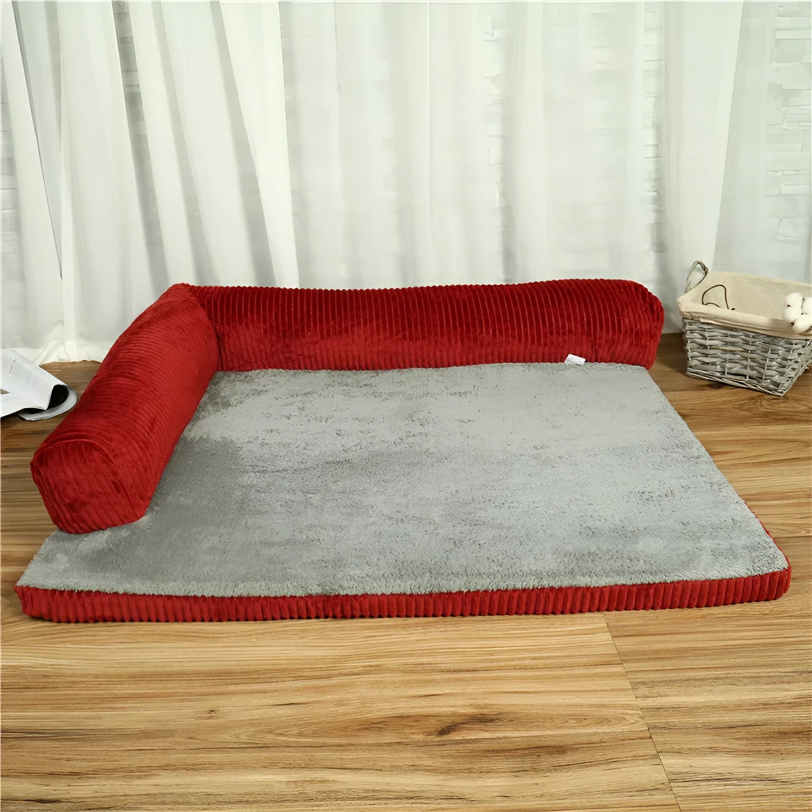 Corduroy pet sofa dog bed with bolster, shown in a grey colour on a wooden floor.