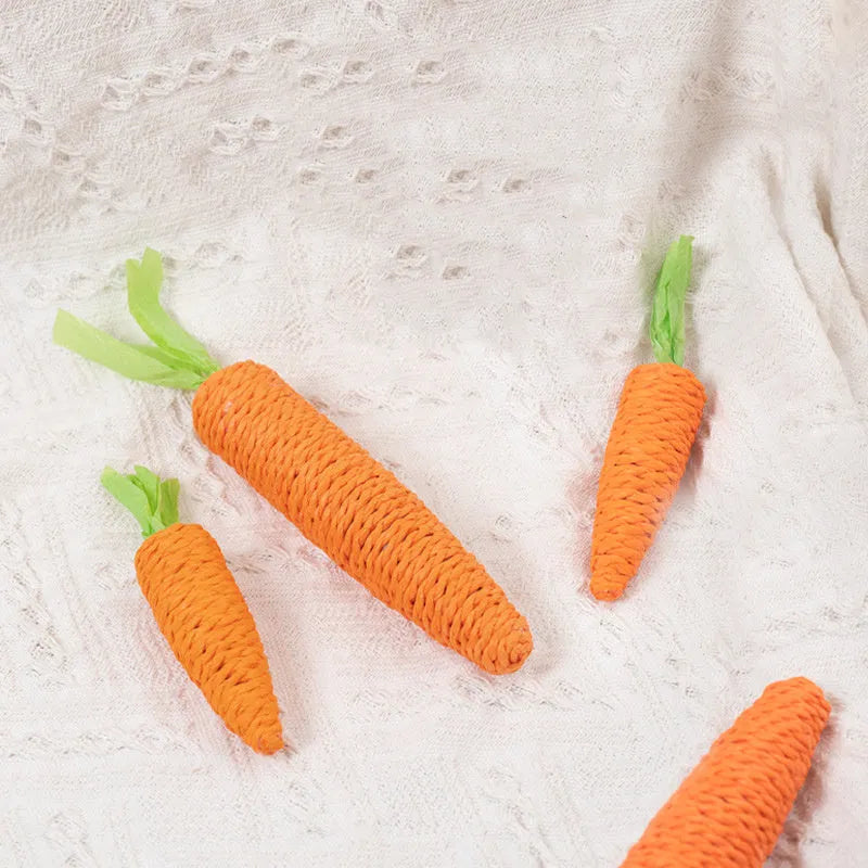 Bundle of cat toys including carrot-shaped chews, crinkly paper rings, and audible ringing stones in multiple sizes