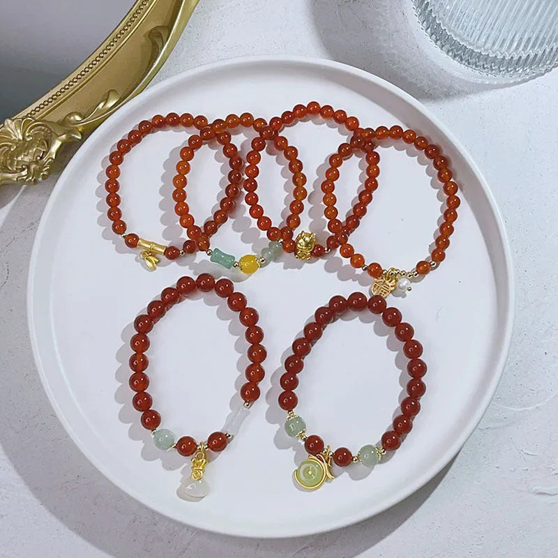 Women's red agate bracelet with manual Chinese dragon and lucky bag designs.