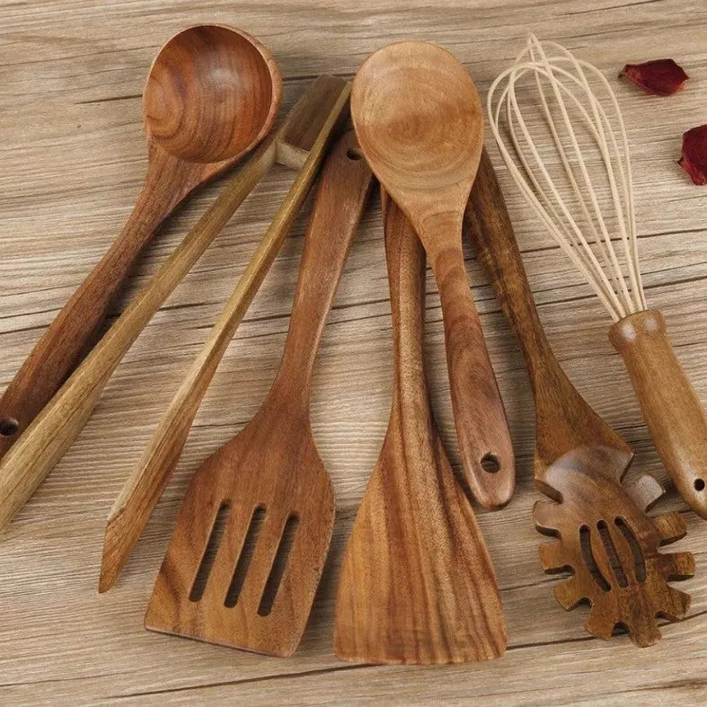 Seven wooden cooking spoons and spatulas with non-slip handles arranged as a set for non-stick pans.