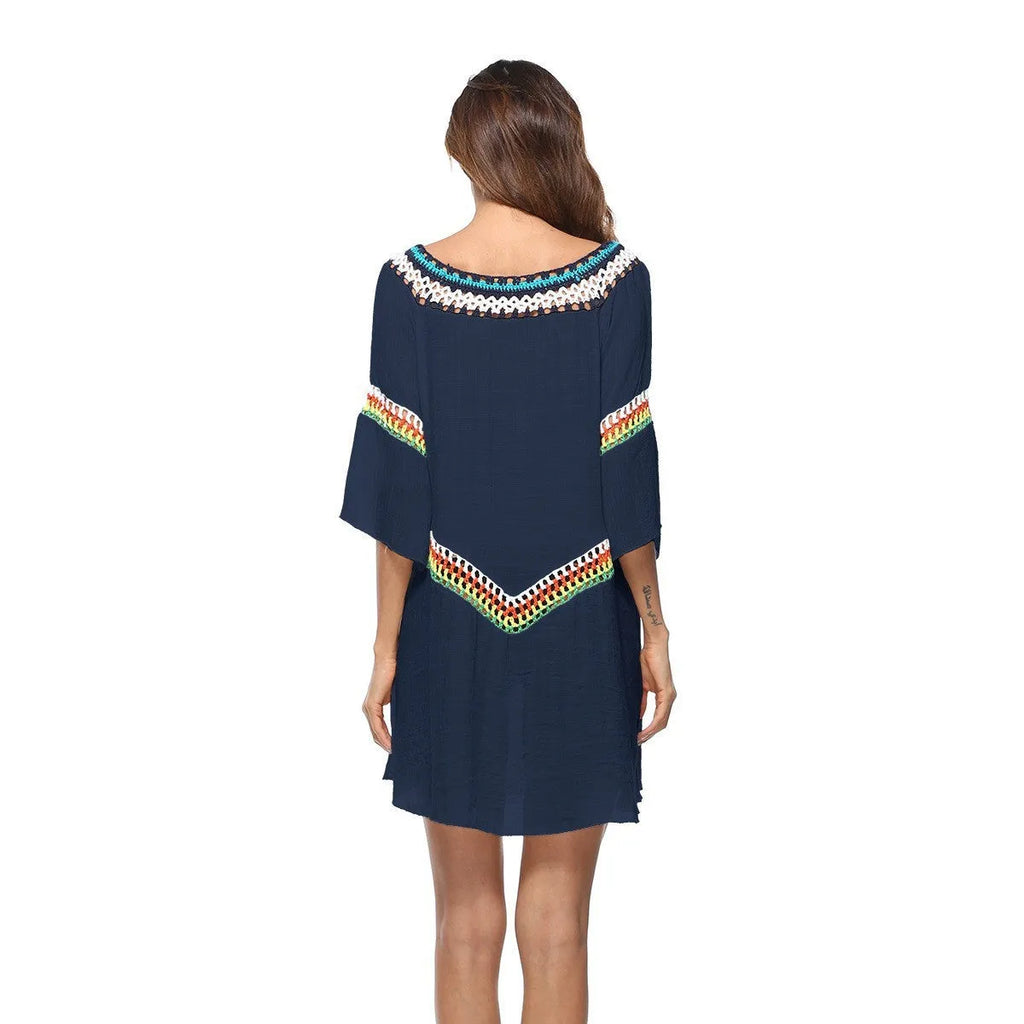 Female model wearing a crocheted ethnic style white sun protection cover-up on the beach.