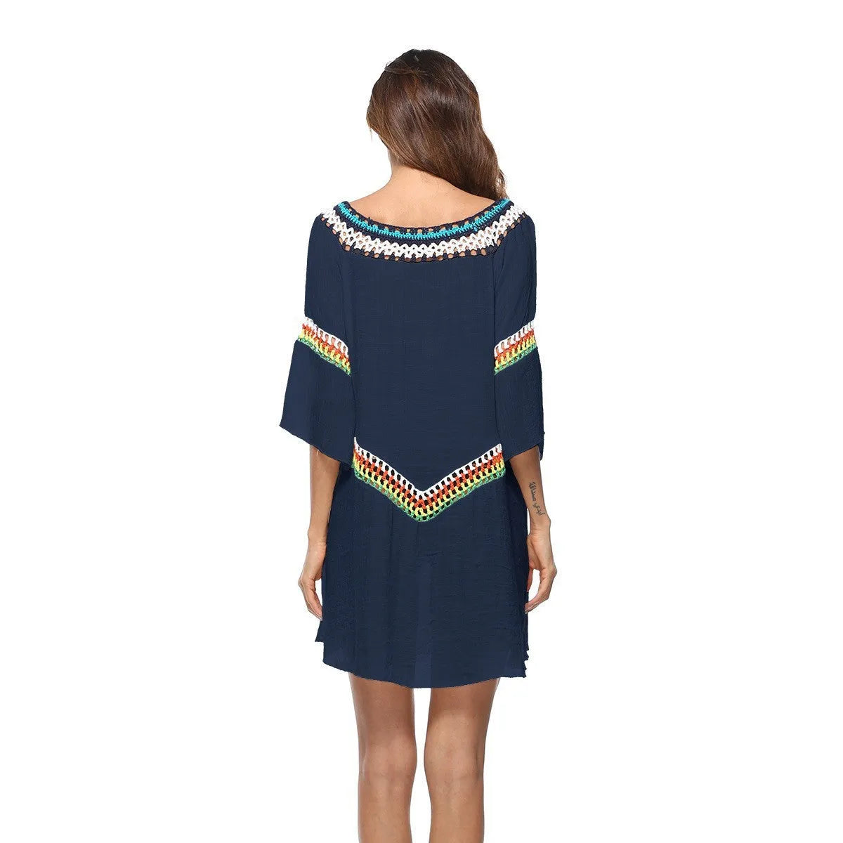 Female model wearing a crocheted ethnic style white sun protection cover-up on the beach.