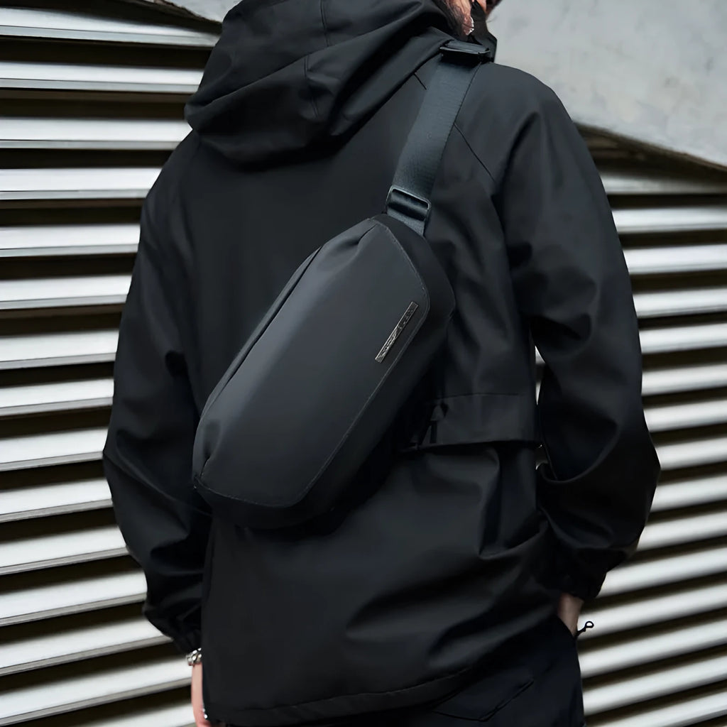 Black Oxford cloth messenger bag for men with visible stitching, shown for one-shoulder carry.