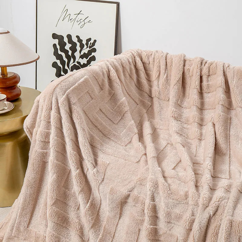 A thick, solid-colour flannel blanket draped over a modern grey sofa.
