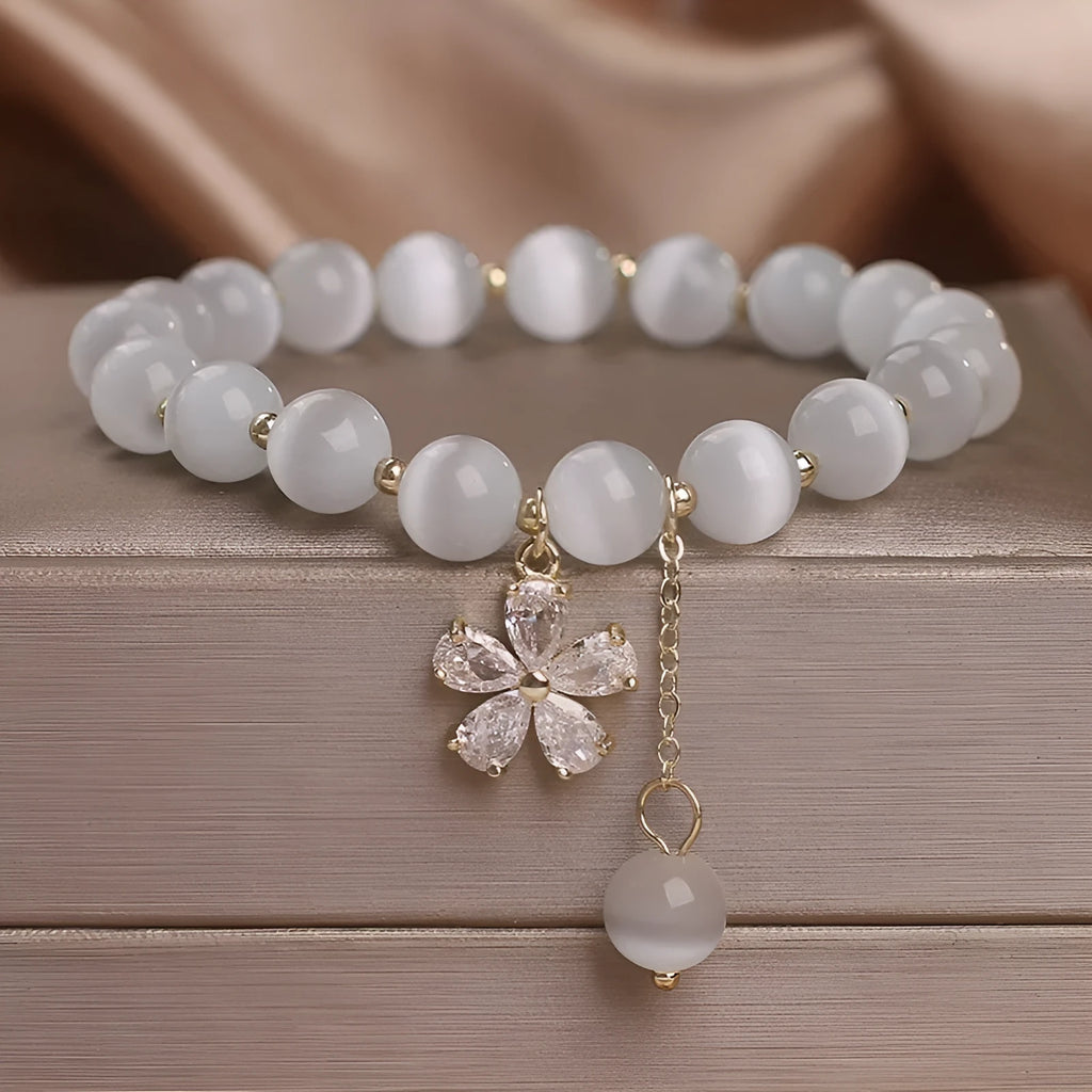 Women's single loop white cat's eye stone bracelet with flower tassel and morganite safety buckle.