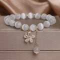 Women's single loop white cat's eye stone bracelet with flower tassel and morganite safety buckle.