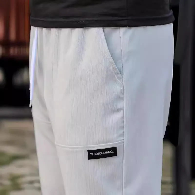 Men's polyester trousers in light grey, shown flat, with a size label indicating S-XXXL range.