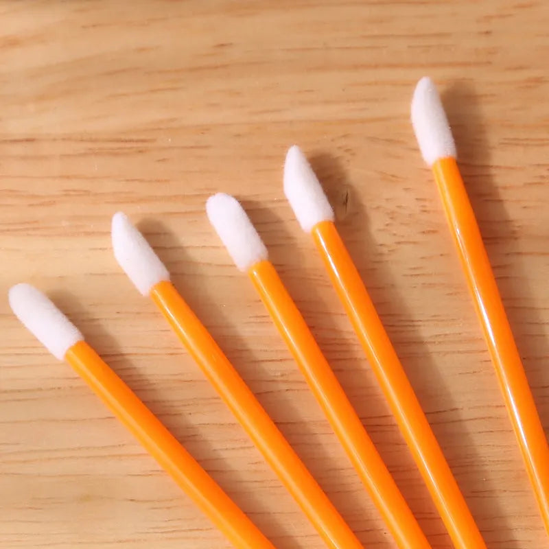 Pack of disposable flocked lip brush applicators with coloured handles on a white surface.