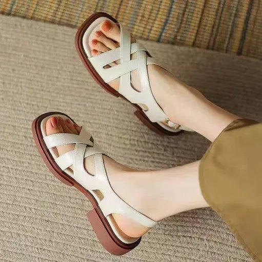 Women's glossy black patent leather sandals with a square toe and low heel on a rubber sole.