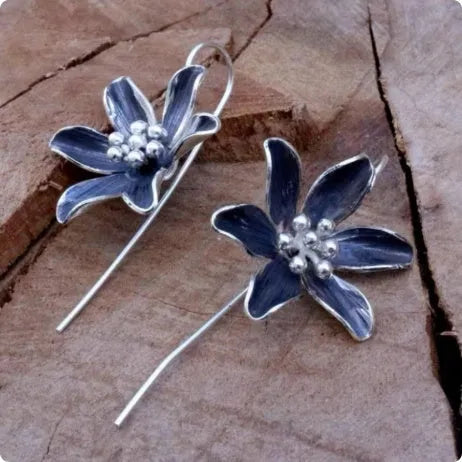 A pair of simple purple flower-shaped alloy earrings for women on a white background.
