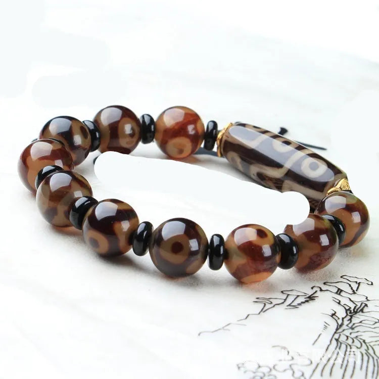 Distressed agate Tibetan bead bracelet with three-eye motifs and polished finish.