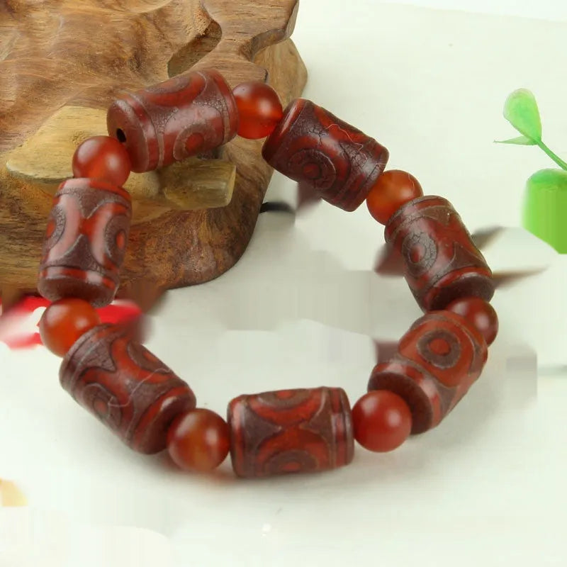 Distressed agate Tibetan bead bracelet with three-eye motifs and polished finish.