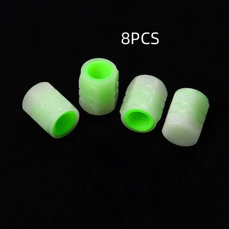 Set of four rubber luminous valve caps for car tyres on a dark background.