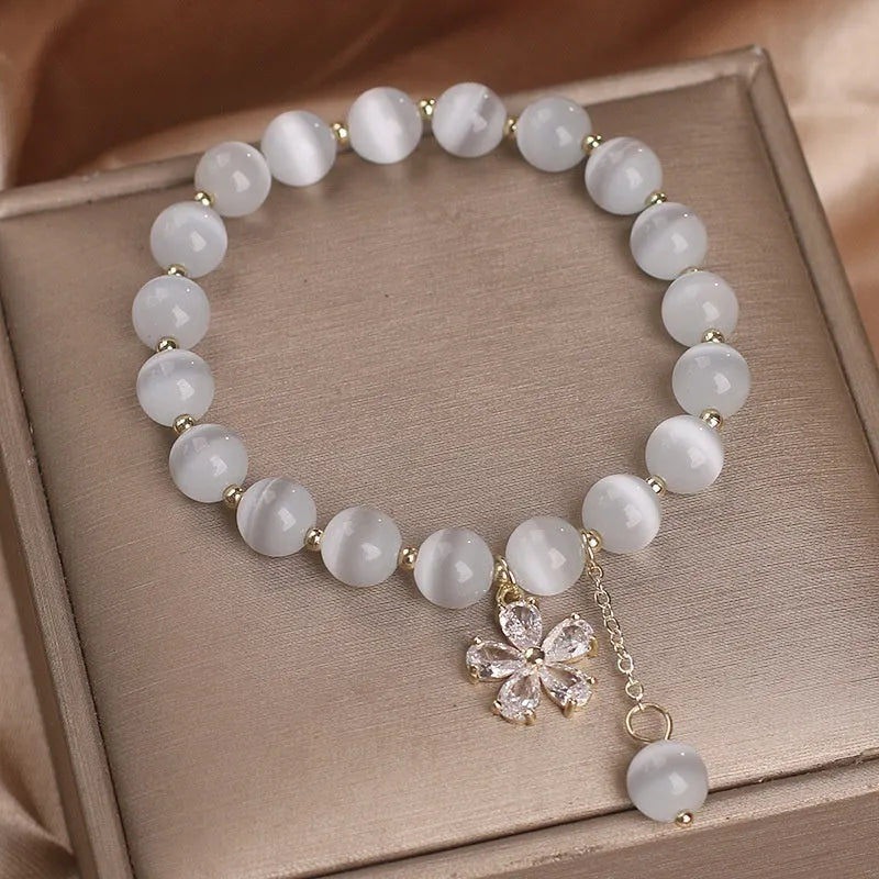 Women's single loop white cat's eye stone bracelet with flower tassel and morganite safety buckle.